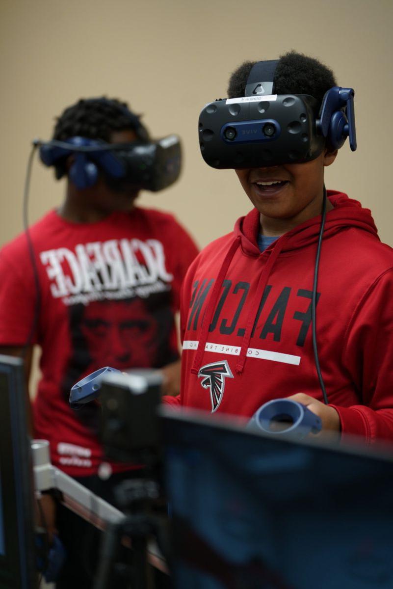 An African American male smiles wearing VR equipment.